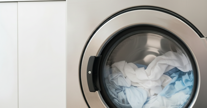 Customer's clothes are being washed in a commercial laundry washer.